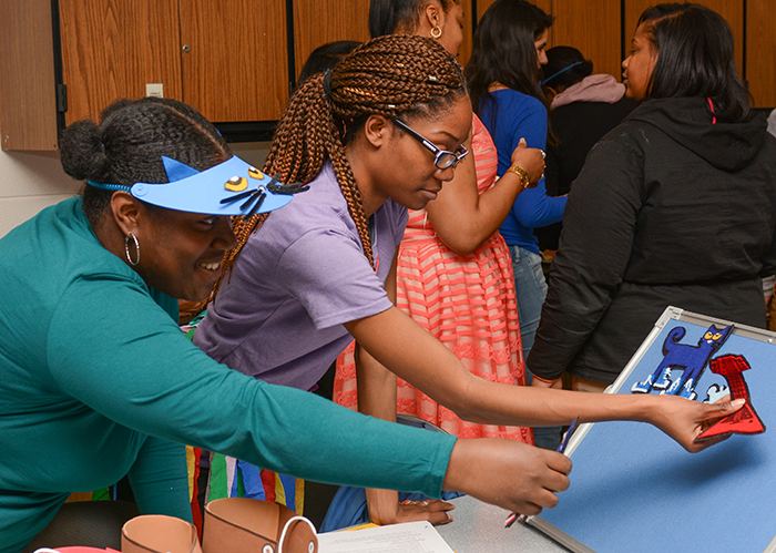 Two female early childhood education students work on a display.