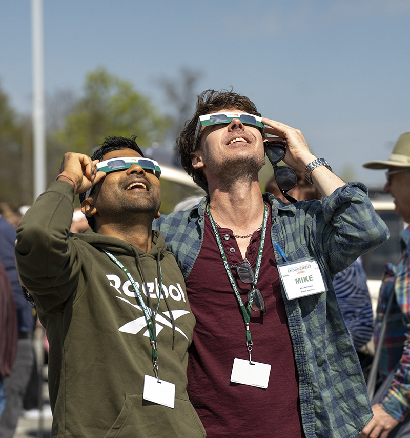 Two men looking at the solar eclipse through glasses.