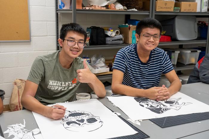 Two art exploration students creating art and smiling