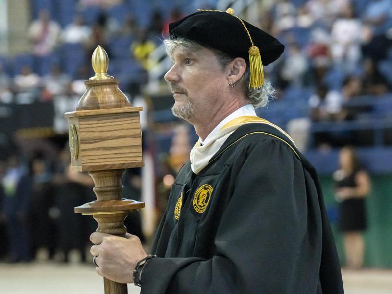 Brian Barbour, English instructor, holds the commencement mace during the ceremony.