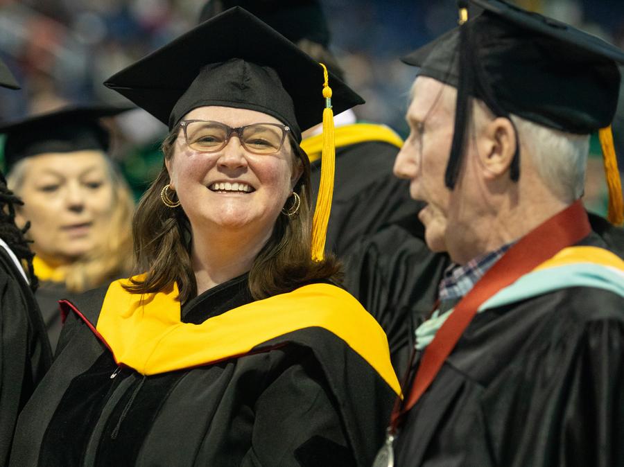 Three faculty members mingle during the graduation ceremony procession.