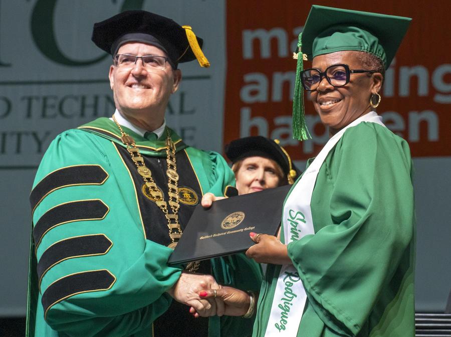 GTCC President Tony Clarke hands a diploma to a student.