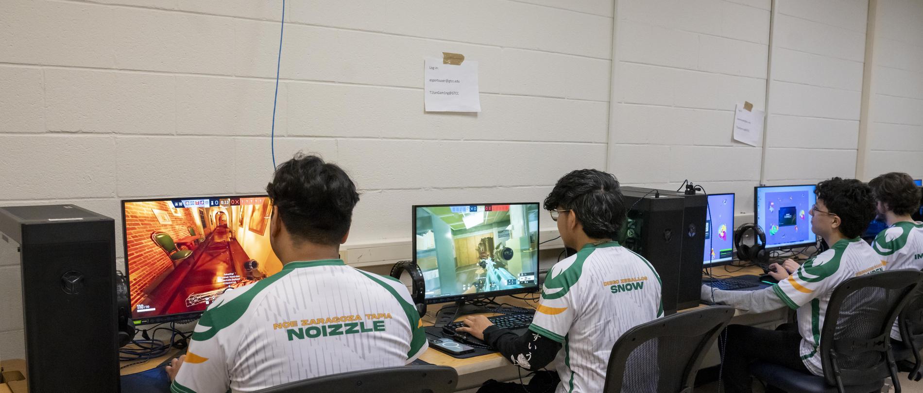 Esports team members play video games at computers.