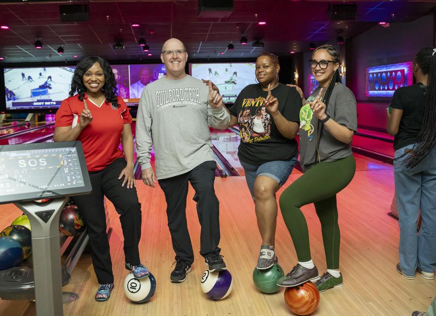 Dr. Anthony Clarke, second from left, and several female students have a foot on a bowling ball.