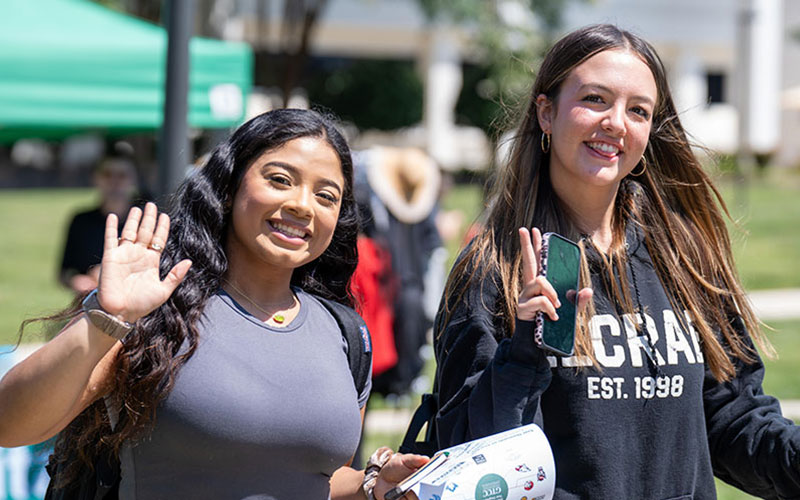 Two GTCC students walking and waving on Jamestown campus