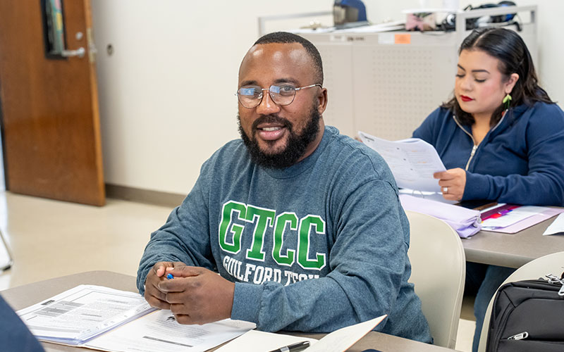 GTCC student sitting at classroom table while smiling