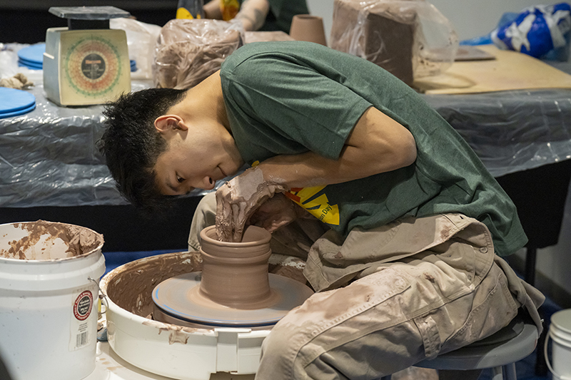 A student works on a pottery wheel at the 2024 Student Presentation Day.
