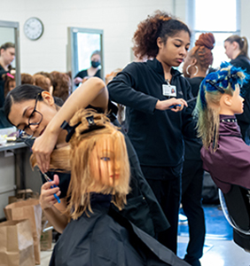 Students practice haircuts on mannequin heads in the cosmetology program.