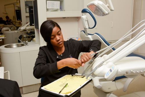 Dental assisting student works on equipment.